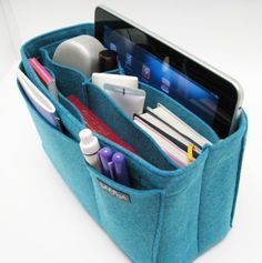 a cell phone is in the pocket of a blue bag with pens, pencils and other office supplies