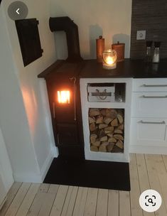 a wood burning stove sitting inside of a kitchen next to a pile of firewood