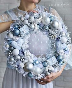 a woman holding a wreath with ornaments on it