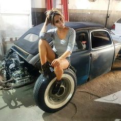 a woman sitting on top of an old car