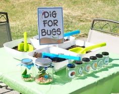 a table topped with lots of bottles and containers filled with stuff next to a sign that says dig for bugs