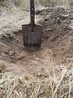 a shovel stuck in the ground next to a dirt hole with grass growing on it