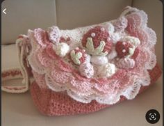 a crocheted purse with pink and white flowers on the front, sitting on a couch