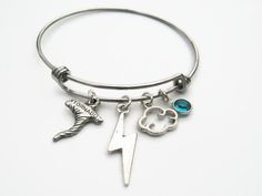 Hand crafted and personalized with love, this storm chaser inspired expandable bangle bracelet features lead/nickel free: antiqued silver tone Lightning bolt charm, Cloud charm and pewter Tornado charm with genuine Swarovski birthstone crystal on an adjustable stainless steel bangle bracelet. Bracelet measures 60/65mm in diameter and fits 6-8.5 inch wrist size. Please note you will need to expand this bracelet over your hand. This bracelet is Ready to Ship. CHOOSE your birthstone crystal at chec Adjustable Themed Charms Jewelry, Customizable Adjustable Stainless Steel Charm Bracelet, Customizable Themed Jewelry Bracelet, Adjustable Fandom Bracelets As Gift, Personalized Fandom Jewelry Gift, Fandom Style Personalized Jewelry Gift, Adjustable Hypoallergenic Themed Jewelry, Themed Hypoallergenic Adjustable Jewelry, Tornado Clouds