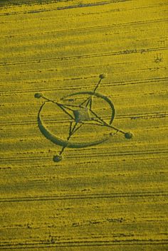 an aerial view of a yellow field with a bicycle in the center and two spokes attached to it