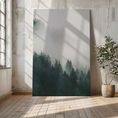 an empty room with a painting on the wall and a potted plant next to it