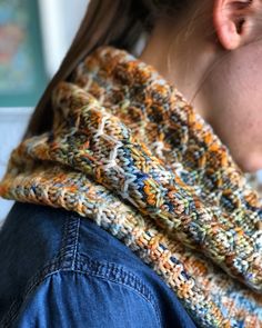 a close up of a person wearing a knitted neckwarmerl and denim jacket