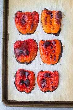 four pieces of bread with red fruit on them sitting on a baking sheet in the shape of hearts