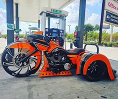 an orange motorcycle parked in front of a gas station