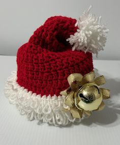 a red and white knitted hat with a gold bell on the side, sitting on a table