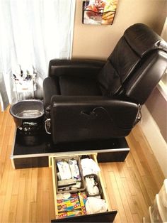 a black recliner chair sitting on top of a wooden floor next to a window