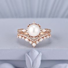 a white pearl and diamond ring sitting on top of a table