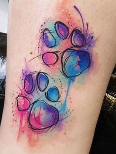 a watercolor tattoo on the leg of a woman's legs with an animal paw print