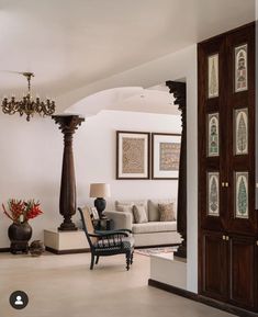 a living room filled with furniture and a chandelier hanging from the side of it