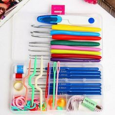 a plastic container filled with lots of different colored pens and scissors on top of a white table