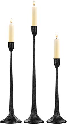 three black candlesticks with one lit candle in the middle and two on each side