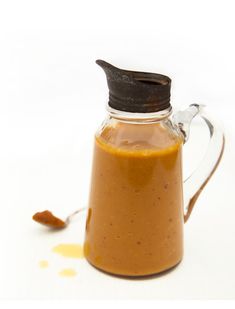 a glass carafe filled with peanut butter on top of a white table