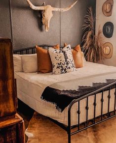 a bed that has some pillows on it and a cow skull mounted to the wall