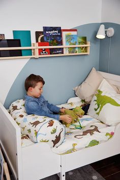 a young boy sitting in his bed reading a book