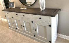 a white dresser with drawers and a mirror on it's sideboard in a room