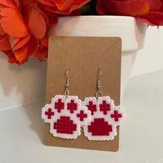 a pair of red and white pixelated heart earrings sitting on top of a card