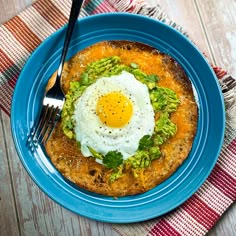 a blue plate topped with an egg and guacamole on top of it