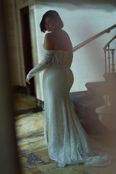 a woman in a white dress is standing on the stairs with her hands behind her back