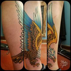 an eagle tattoo on the leg of a woman's legs, with blue and yellow wings