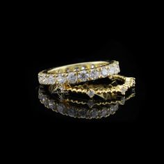 two gold rings with diamonds on black background