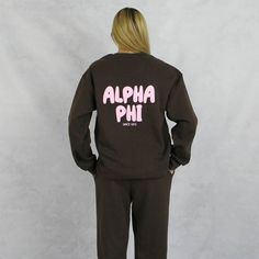 the back of a woman wearing a brown sweatshirt and pants with pink letters on it