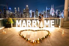 a newly married couple standing in front of a heart - shaped sign that reads marry me