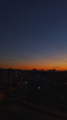 the sun is setting over a city with tall buildings in the foreground and an airplane flying overhead