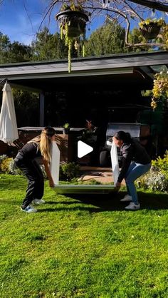 two people are moving furniture in the yard