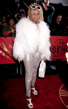 the woman is dressed in white feathers and posing for a photo on the red carpet