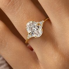 a woman's hand with a yellow gold ring and a white diamond in the center