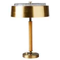 a brass table lamp with a marble top and wooden base, on a white background