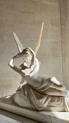 a statue of a woman sitting on top of a white marble bench in a room