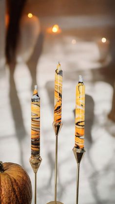 three candles sitting next to each other on top of a table with an apple in the foreground