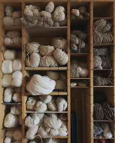 many balls of yarn are on shelves in a storage area, and one is white