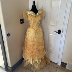 a yellow dress is on display in front of a white door with a black handle