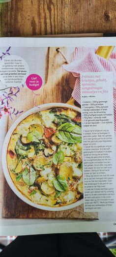 an article in the magazine about food and drink is displayed on a wooden table with flowers