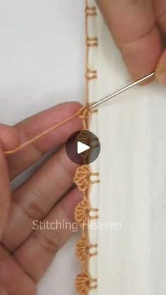 someone is stitching on the edge of a piece of fabric with a needle and thread