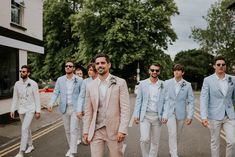 a group of men in suits and ties walking down the street with one man wearing sunglasses