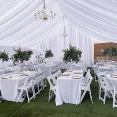 tables and chairs are set up under a white tent with flowers on them for an event