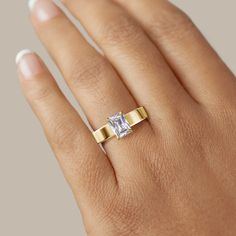 a woman's hand with a yellow gold ring and a white diamond on it