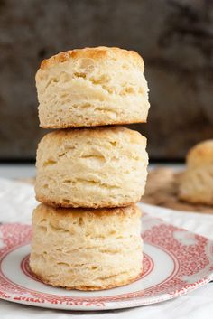 three biscuits stacked on top of each other on a red and white plate next to another biscuit