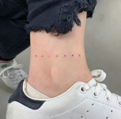 a woman's foot with small colorful dots on the lower part of her ankle