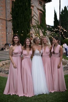 four bridesmaids in pink dresses posing for a photo at their wedding reception outside