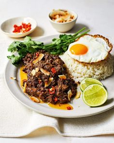 a white plate topped with rice and meat next to an egg on top of it