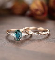 two gold rings with blue and white stones on them sitting on a wooden table next to an apple